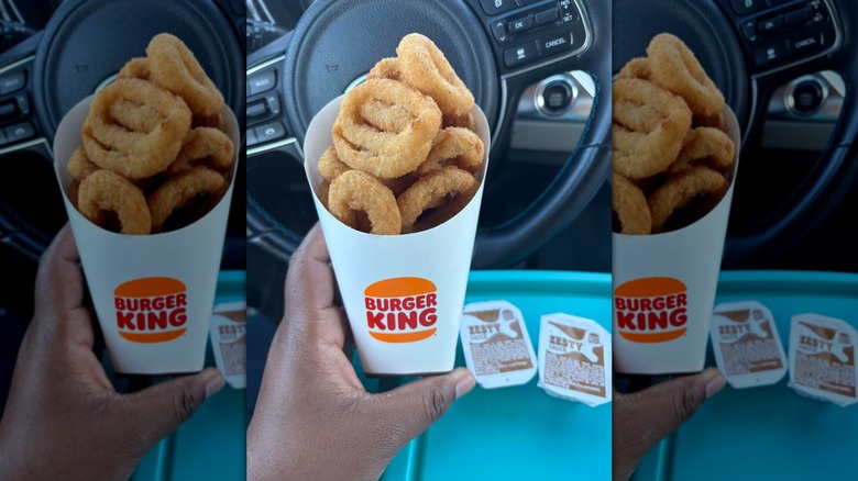 Hand holding carton of Burger King onion rings