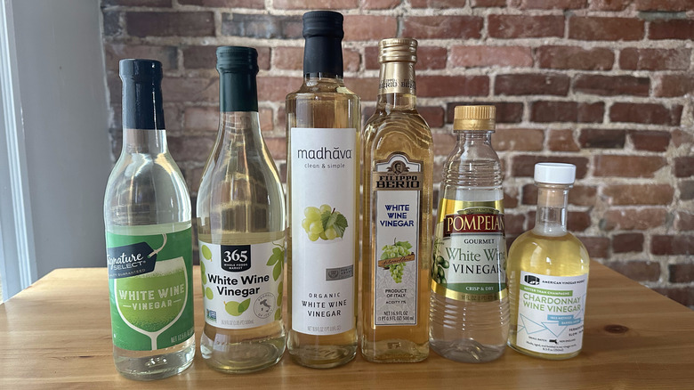Six bottles of white wine vinegar on wooden table