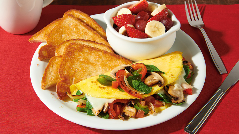 Denny's loaded veggie omelet on white plate on red placemat