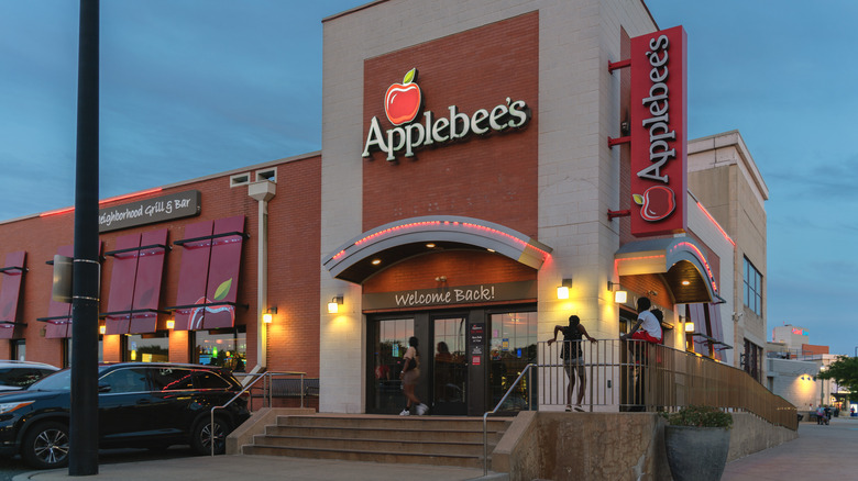 Exterior view of people outside of an Applebee's in the evening