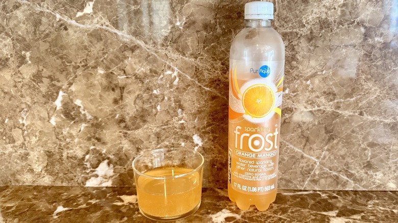 Orange Mango  Frost Water bottle next to a little poured in a glass