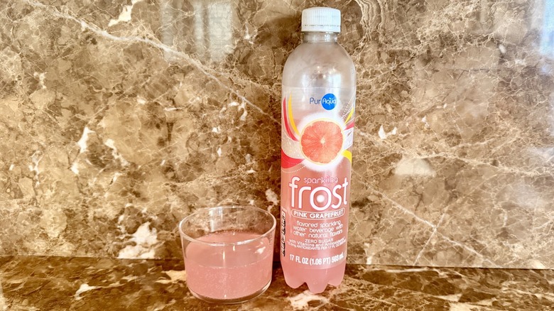 Pink Grapefruit Frost Water bottle next to a little poured in a glass
