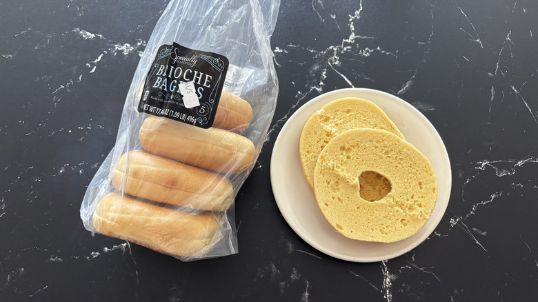 Aldi Specially Selected brioche bagel pack next to a bagel sliced in half served on a white plate