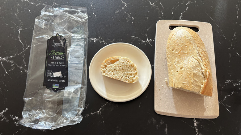 Aldi take and bake Italian bread wrapper next to a slice of bread on plate and the whole loaf on a cutting board