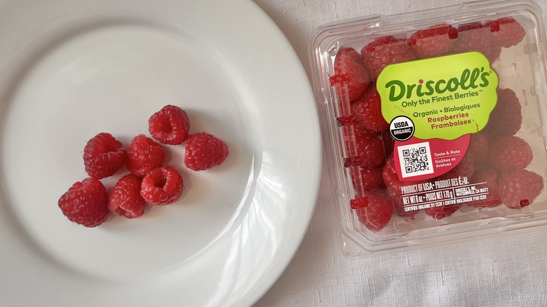 Box of raspberries and fruit on a plate