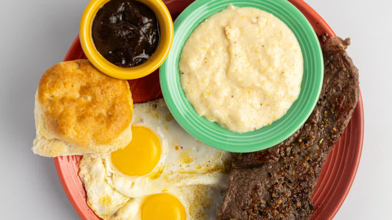 Steak, eggs, biscuit, cranberry apple butter, and grits on plate at Flying Biscuit Cafe