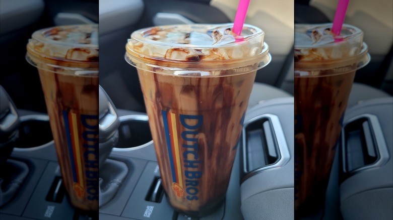 Cocomo in clear plastic takeaway cup streaked with chocolate, resting on car's center console