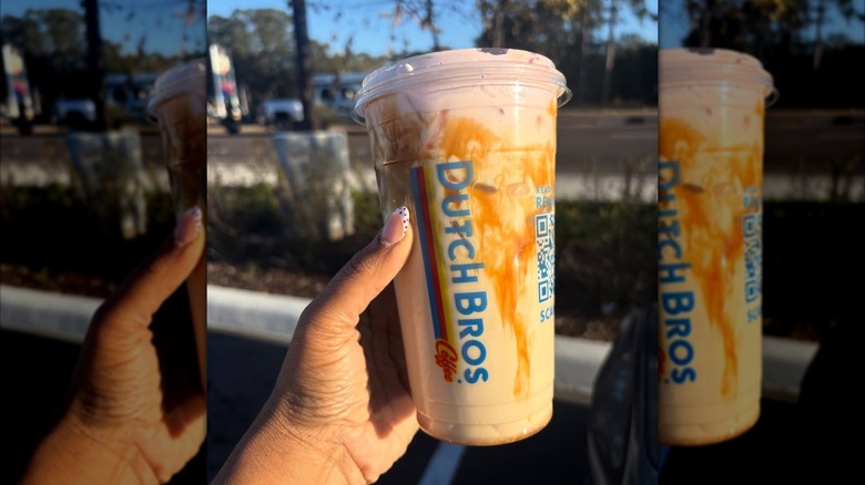 Hand holding iced Golden Eagle with strawberry foam top in parking lot