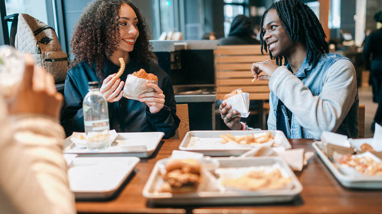 Two people sitting at a West Coast fast food chain table and eating together