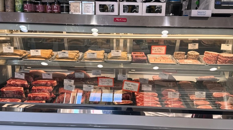 A selection of meat on display behind glass in a butcher shop