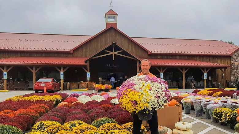 Man holding flowers in front of large red market