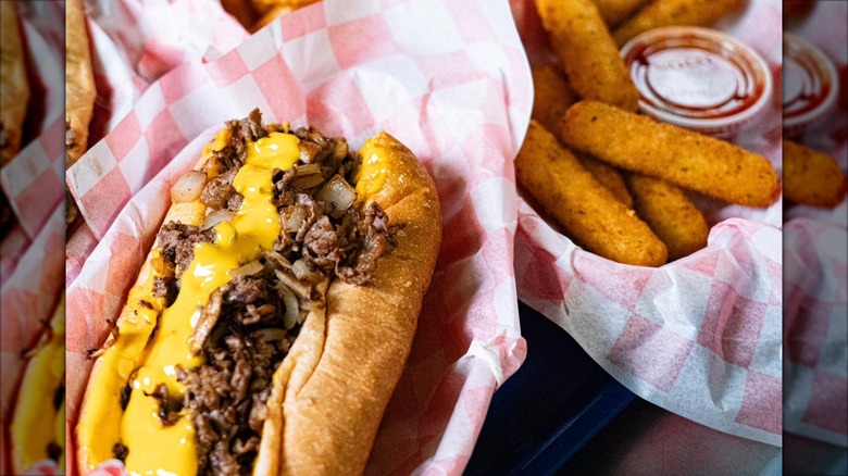 Cheesesteak in basket with paper and side order of mozarella sticks