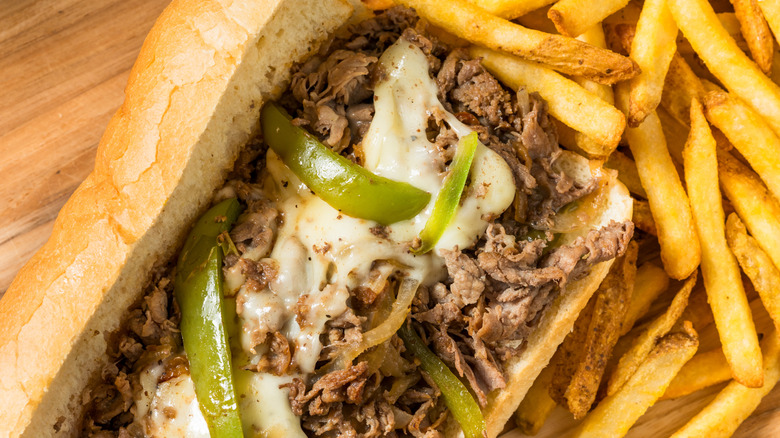 Philly cheesesteak with peppers and onions, fries on the side