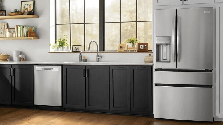 Frigidaire fridge in kitchen beeside sink and countertop with black cabinets and a window