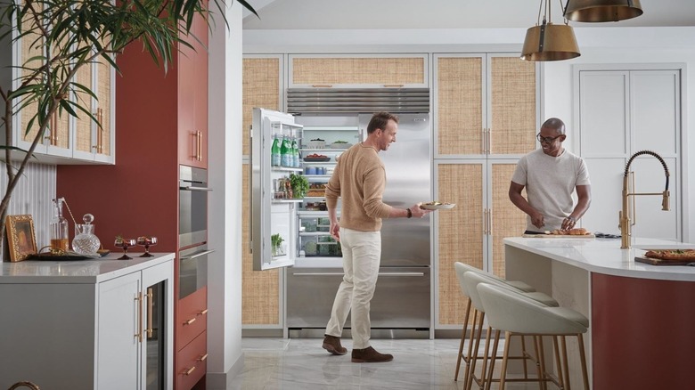 Two men in a spacious kitchen cooking one taking food out of a Sub-Zero fridge