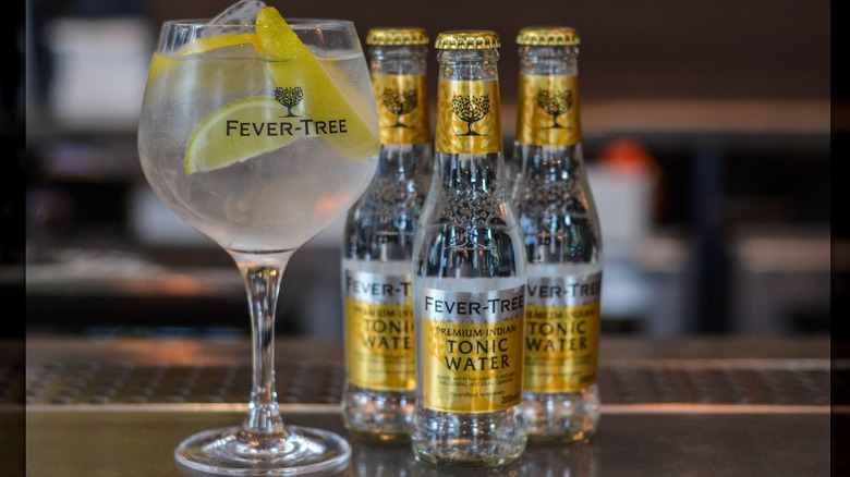 Fever Tree tonic bottles lined up with a cocktail filled with lemon and ice in the front