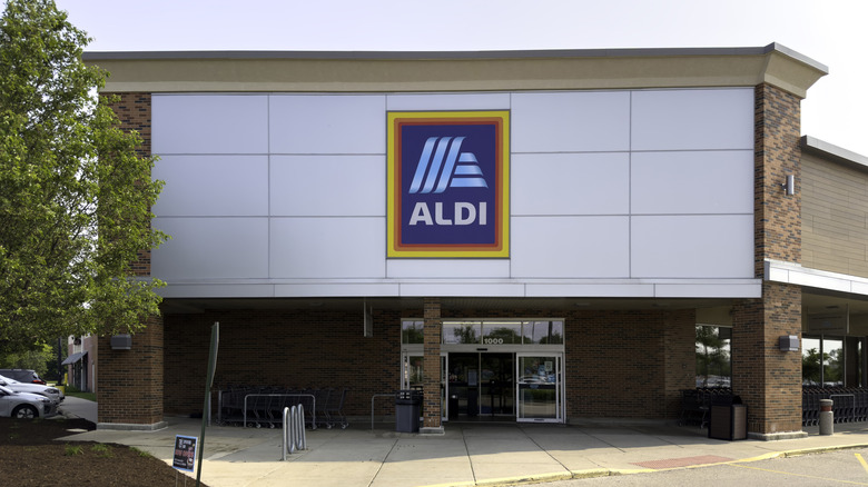 Aldi store front next to tree against cloudy sky