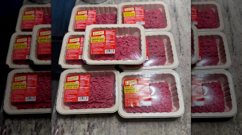 Seven packages of extra lean ground beef on countertop