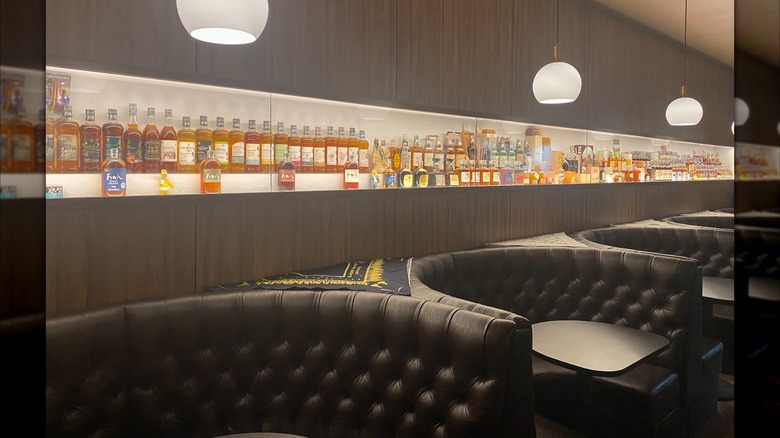 Leather seats and wall of assorted whiskey bottles