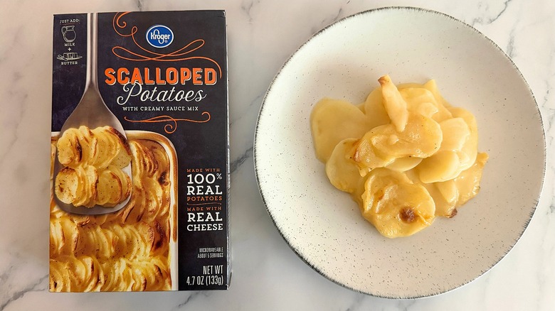 Box of Kroger Scalloped Potatoes next to scalloped potatoes on white plate