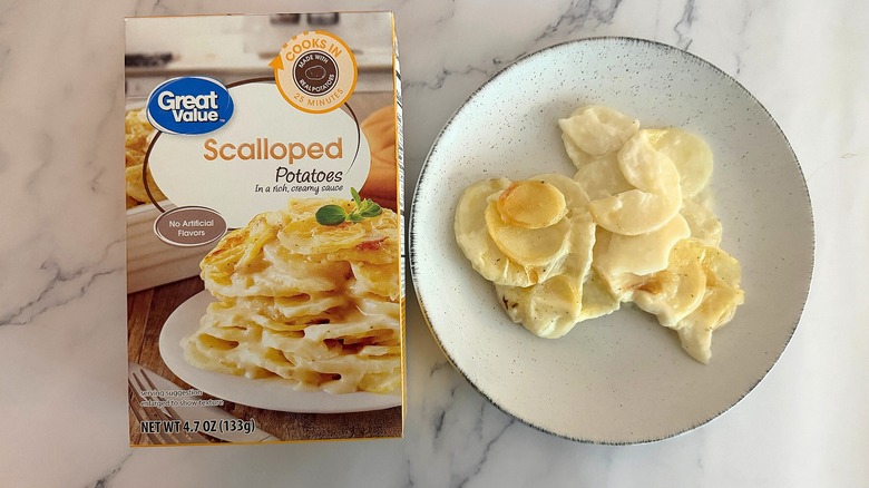 Box of Great Value Scalloped Potatoes next to scalloped potatoes on white plate