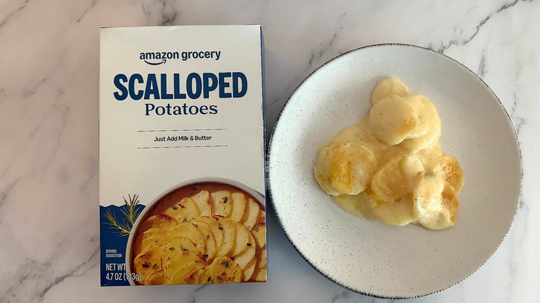 Box of Amazon Grocery Scalloped Potatoes next to scalloped potatoes on white plate