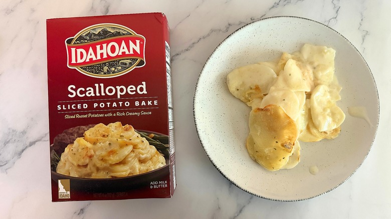 Box of Idahoan Scalloped Potatoes next to scalloped potatoes on white plate