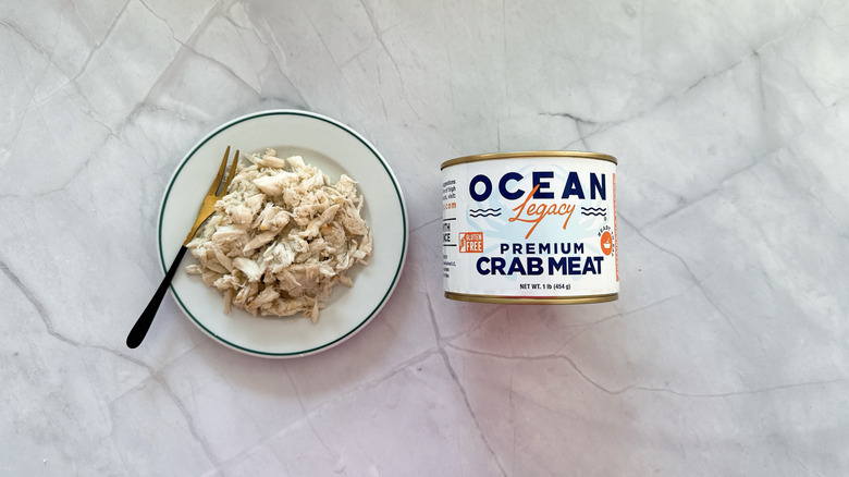 Crabmeat on a plate next to a can of Ocean Legacy crab meat.