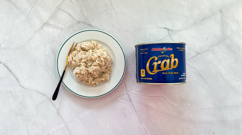 Crabmeat on a plate next to a can of Chicken of the Sea crab meat