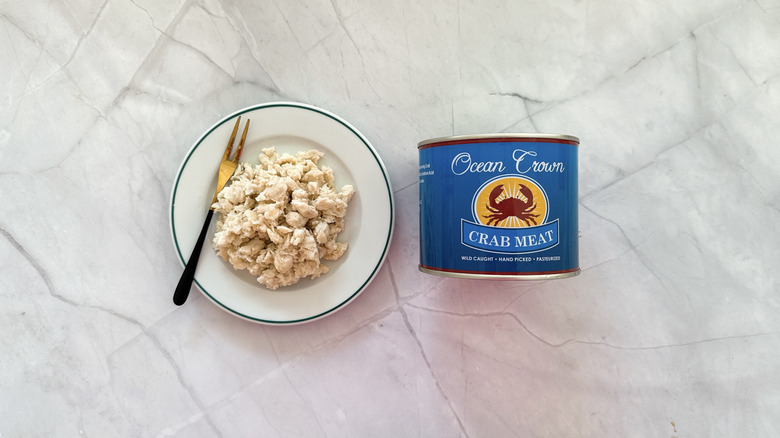 Crabmeat on a plate next to a can of Ccean Crown crab meat.