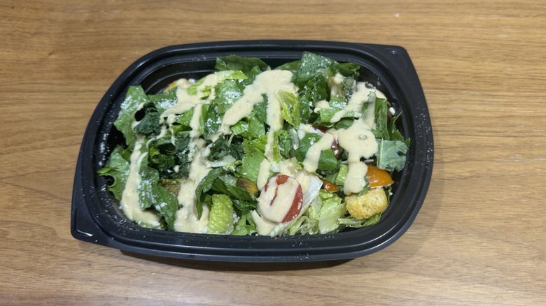 Yard House's kale and romaine Caesar salad on a wooden surface.