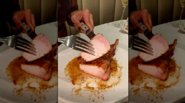 Fork and knife holding piece of Double-Thick Pork Rib Chop at Fleming's Prime Steakhouse
