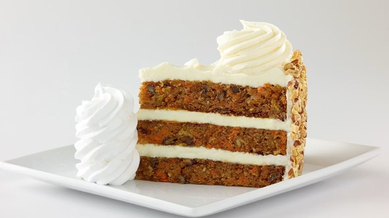The Cheesecake Factory's Carrot Cake sits on a white plate with a mound of icing on the left