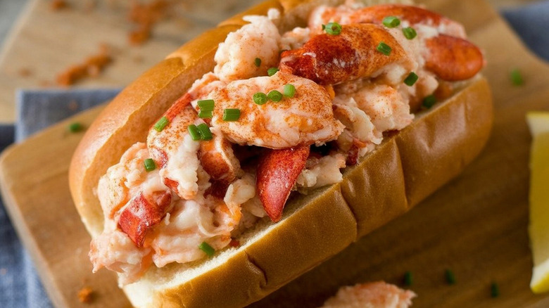 Overstuffed lobster roll sitting on a cutting board.