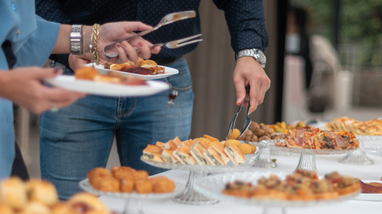 Man and woman placing catering food on white plates