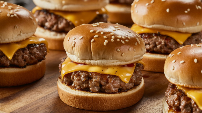 Mini cheeseburgers with melting cheese on a wooden board