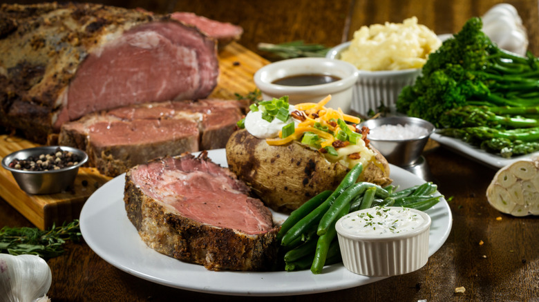Slice of prime rib with a baked potato on a plate