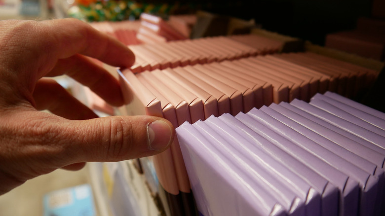 Hand picking chocolate bar from grocery store shelf