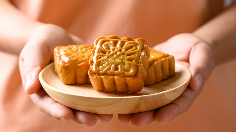 A person holding a plate of mooncakes