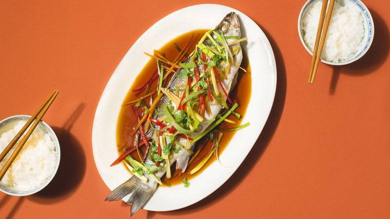 Whole cooked fish on red background