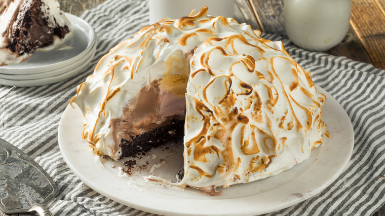 Cut open Baked Alaska on white plate on striped towel