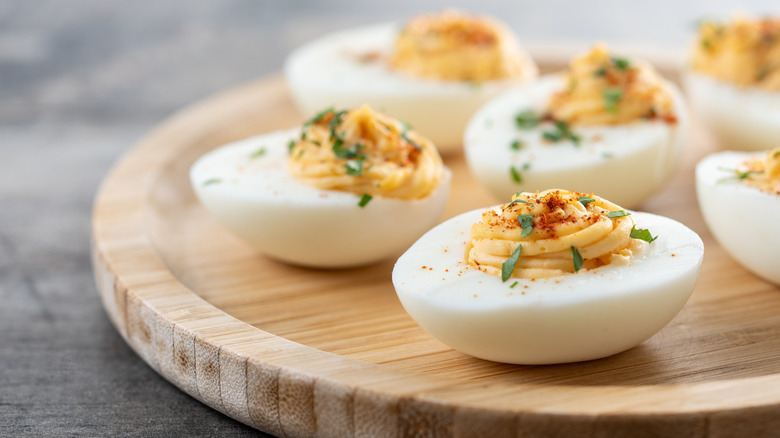 Deviled eggs garnished with herbs on wooden board
