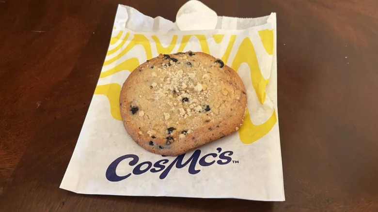 A lemon cookie with blueberries on top of a CosMc's takeaway bag