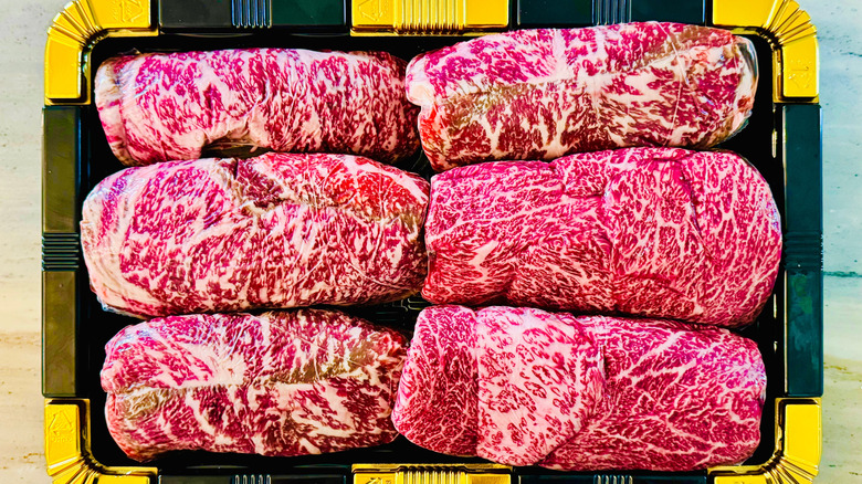Marbled Korean Hanwoo beef steaks neatly arranged in a black and gold tray