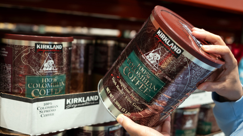 Hands grabbing a container of Kirkland Signature coffee off the shelf