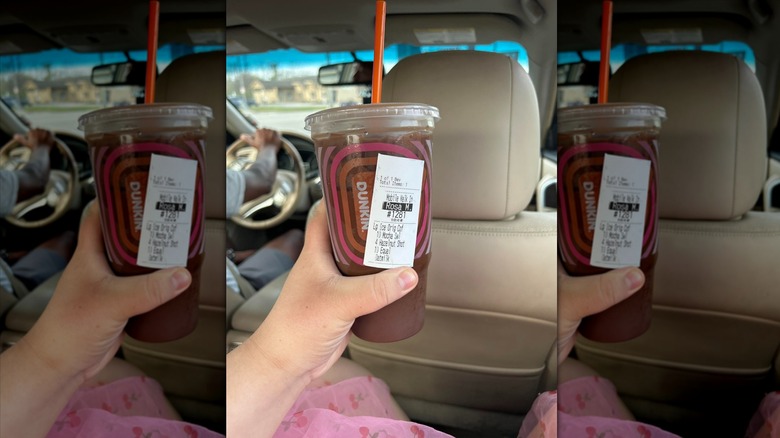 Hand holding cup of hazelnut mocha iced coffee from Dunkin'