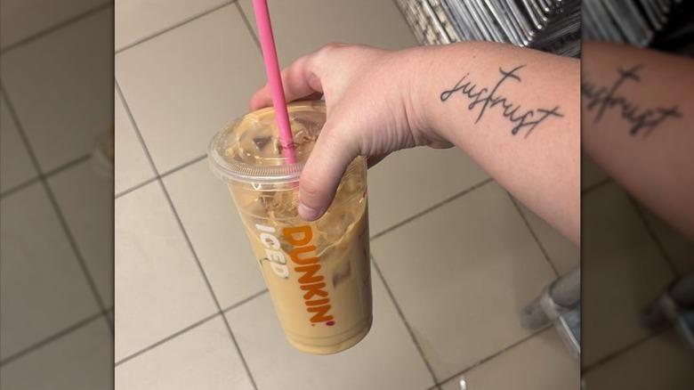 Hand holding Dunkin' iced coffee with blueberry flavor shot