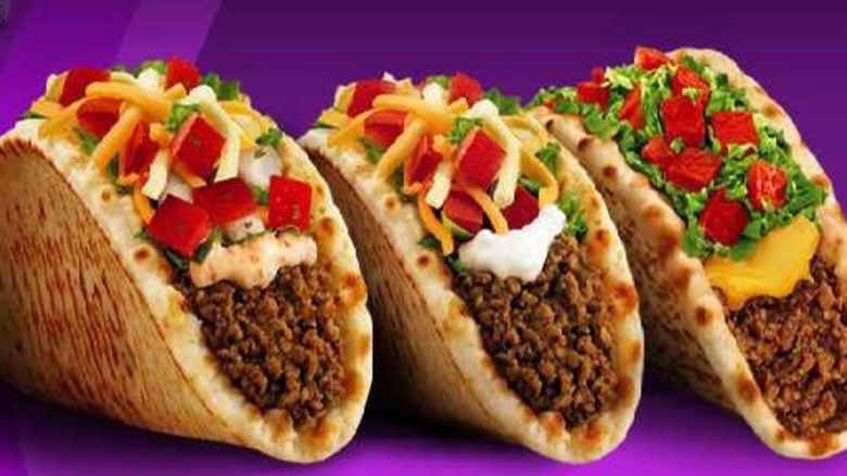Three Taco Bell Gordita tacos on purple background.