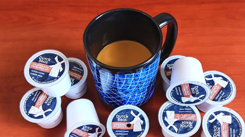 Dutch Bors. chocolate macadamia nut coffee pods on table with black and blue mug of coffee with cream.