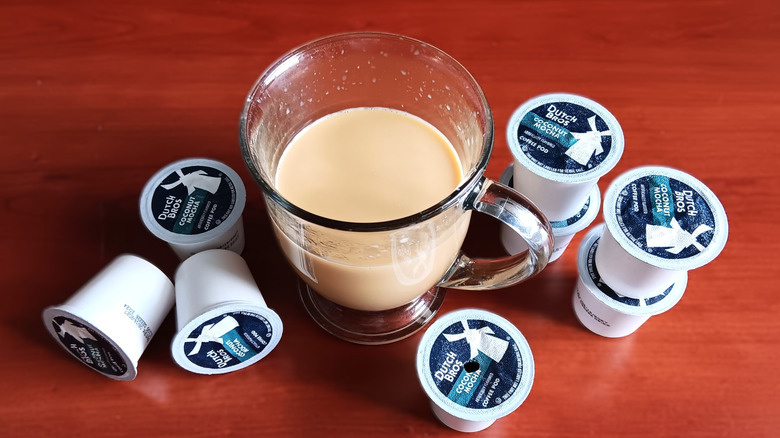 Dutch Bros coconut mocha coffee pods on table with glass mug of coffee with cream